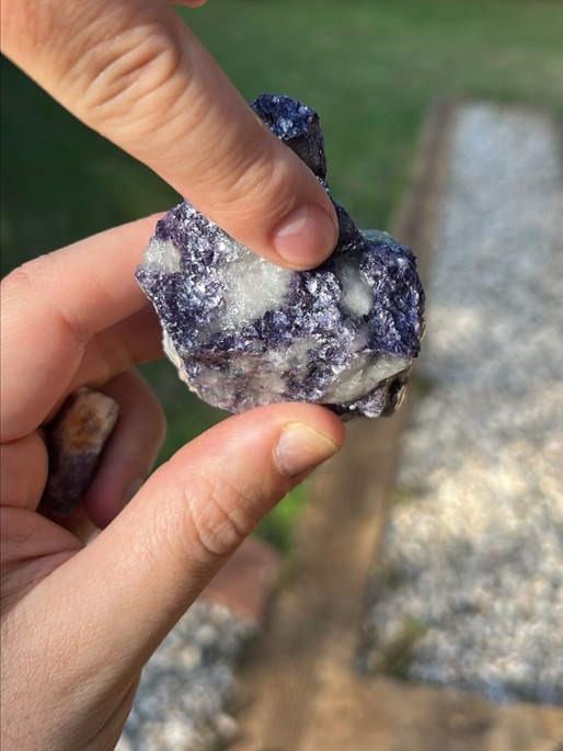 A lithium stone is shown nestled in the hand of two men during CRU's analysts' visit to Zimbabwe's Lithium Industry